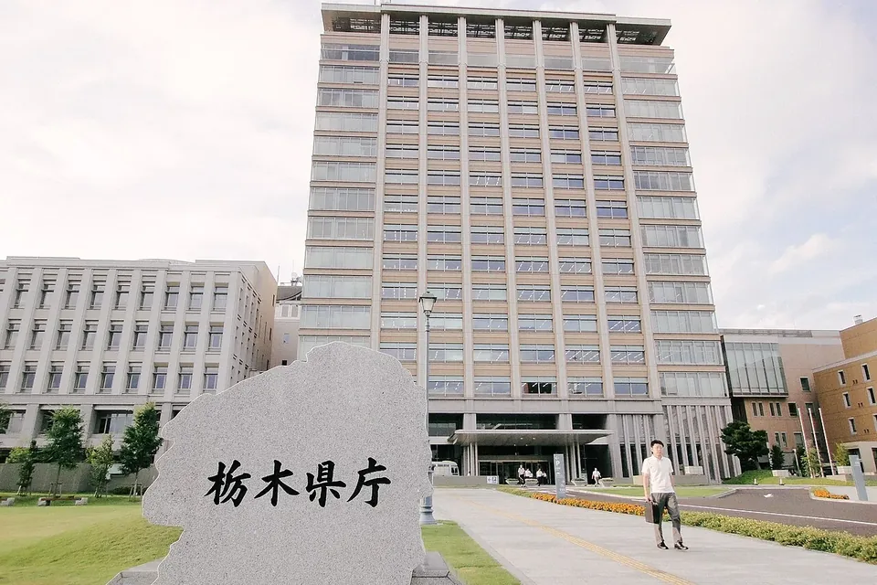 「栃木県庁」と刻まれた石碑の奥にそびえる高層の栃木県庁舎