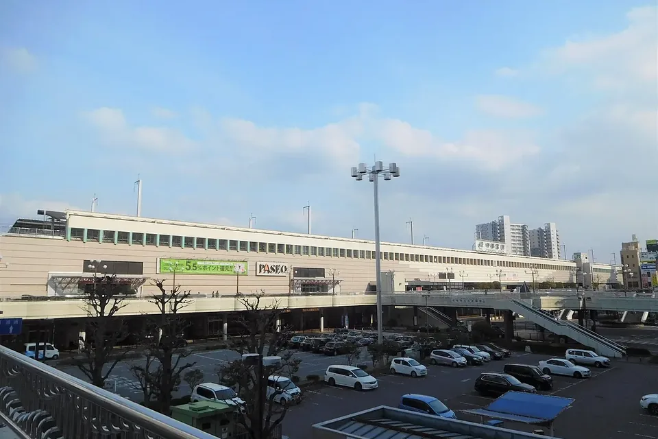 駐車場の向こうに横長の駅ビルが見える、晴れた日のJR宇都宮駅西口