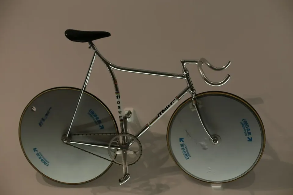 前後輪とも円盤状のディスクホイールを付けた銀色の競技用自転車の展示品